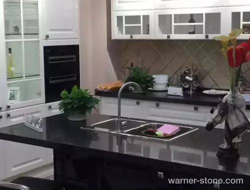 High-gloss black pearl quartz island contrasted with classic white cabinetry